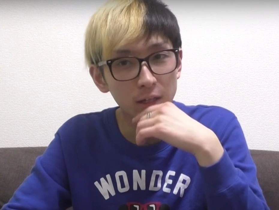 ヒカルさんがYouTube初期動画で青いスウェット姿に黒いウェリントン型メガネを着用しているショット