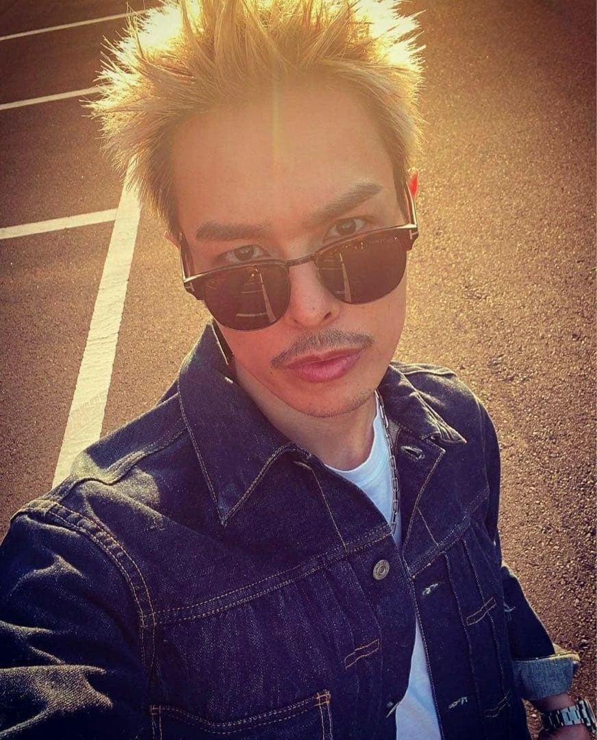 今市隆二さんが夕陽の中デニムジャケットの私服セルフィーでTOM FORDのHenry TF248を着用しているショット