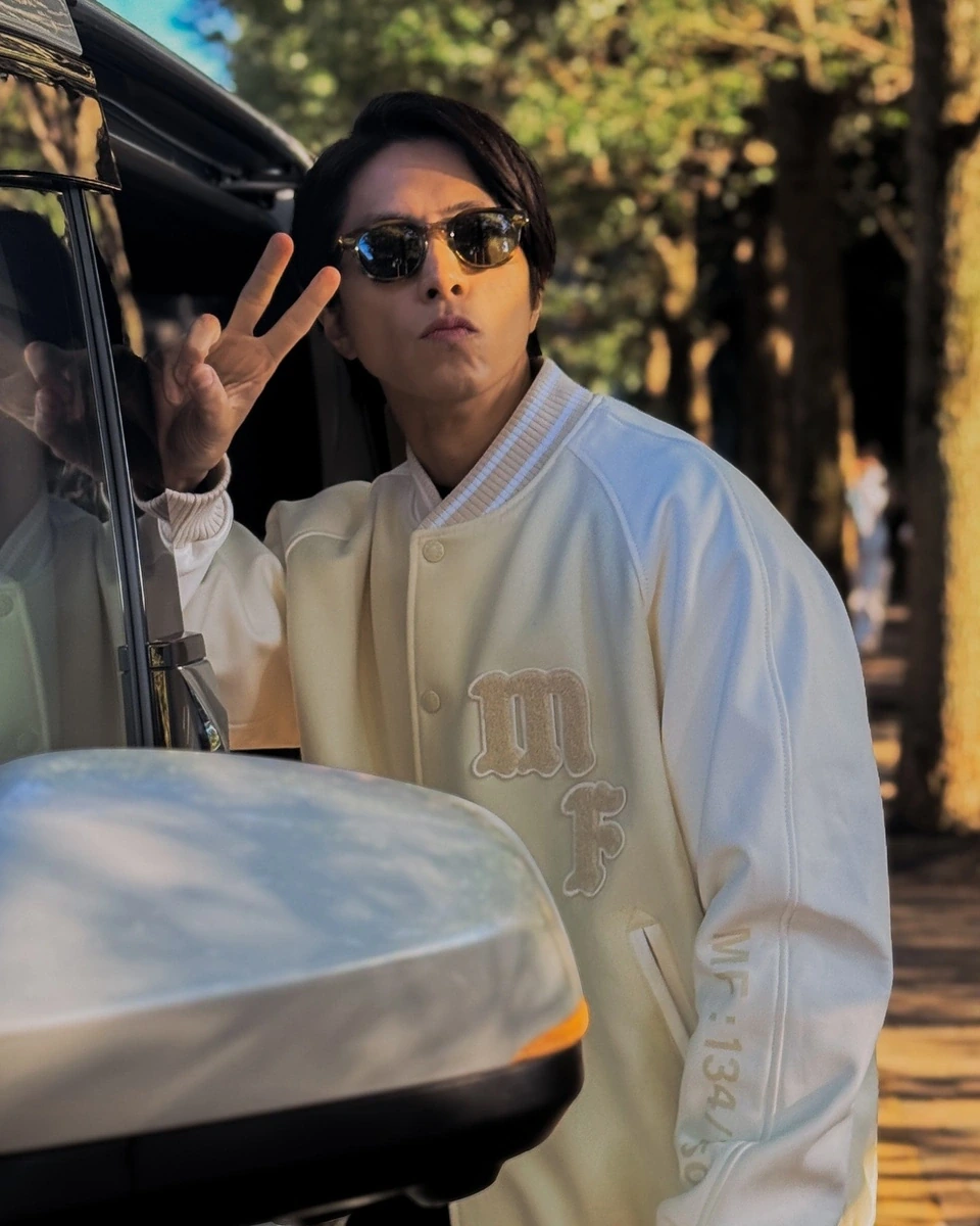 山下智久さんが白いスタジャンにMOSCOTのLEMTOSH SUNを着用しピースサインをするInstagram投稿のショット