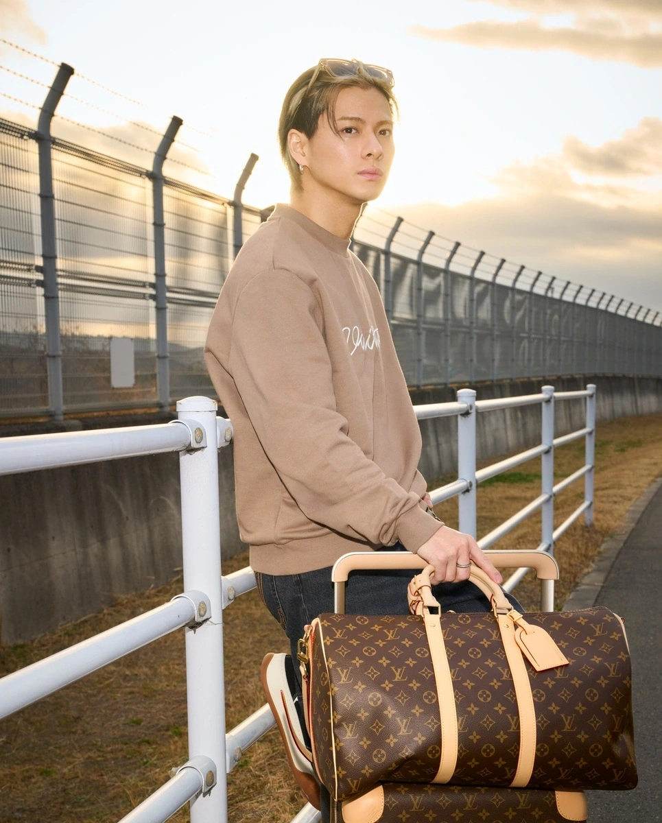 パリ・コレクション出発時の空港私服でルイ・ヴィトンのサングラスを頭にかけた平野紫耀さん。モノグラムのキーポルとトランクを持った夕景ショット